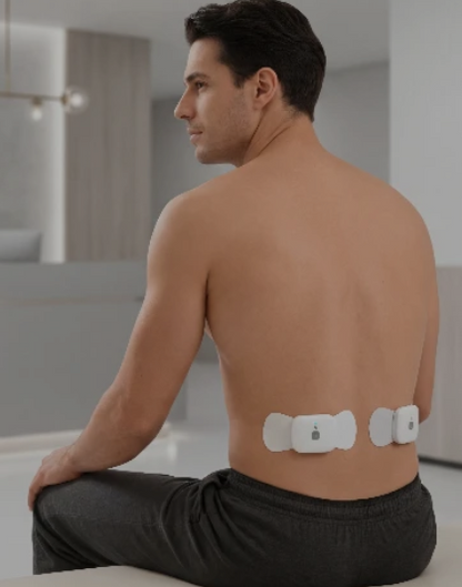 Man with electronic patches on his back in a modern bathroom